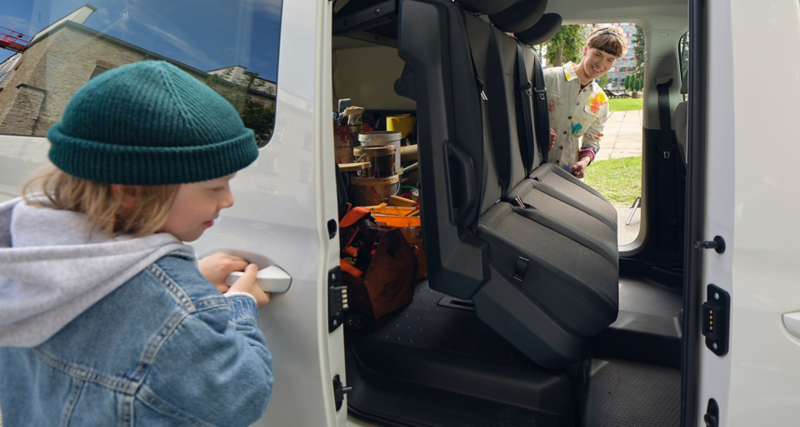 Eine Frau – Malerin und Mutter – klappt die hintere Sitzreihe im VW Caddy Flexible um.