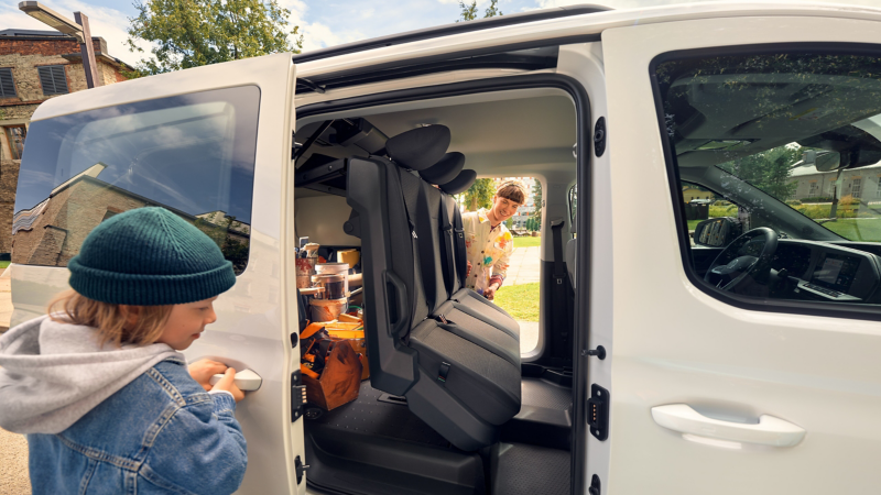 Eine Frau – Malerin und Mutter – klappt die hintere Sitzreihe im VW Caddy Flexible um.