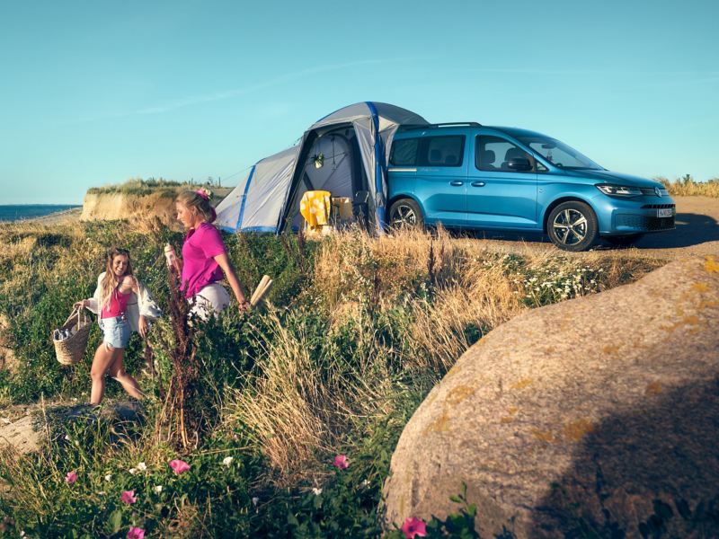 Tält kopplat till bilen på en blå VW Caddy California Maxi parkerad på sanddynerna