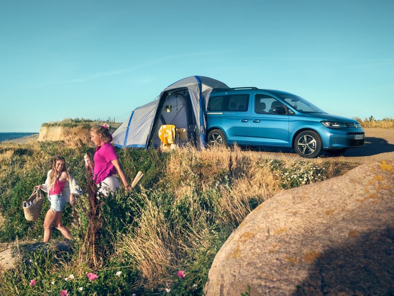 En blå VW Caddy California med tält på en sanddyn