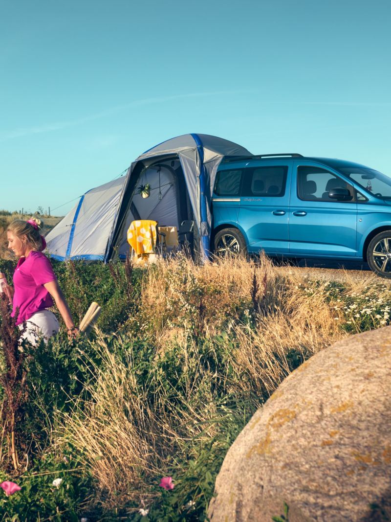 En blå VW Caddy California med tält på en sanddyn