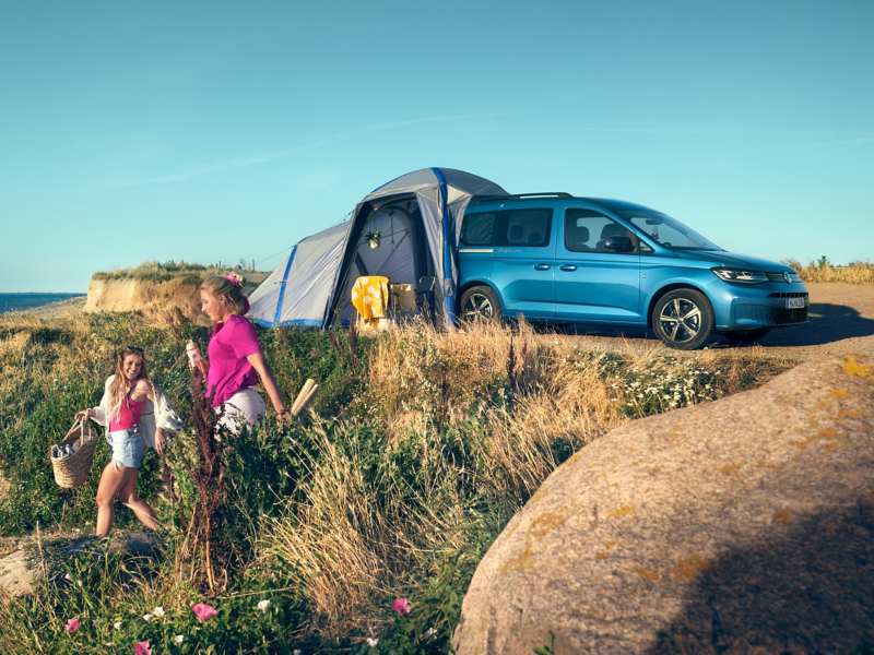 En blå VW Caddy California med tält på en sanddyn