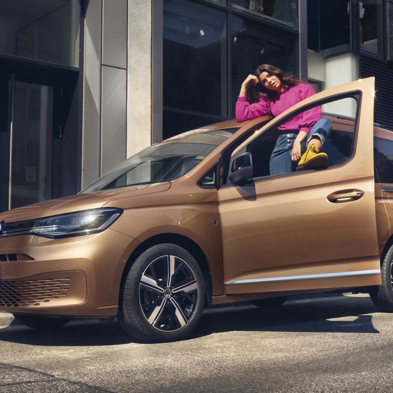 Una giovane donna appoggiata a Nuovo Caddy acquistato con le promozioni Volkswagen