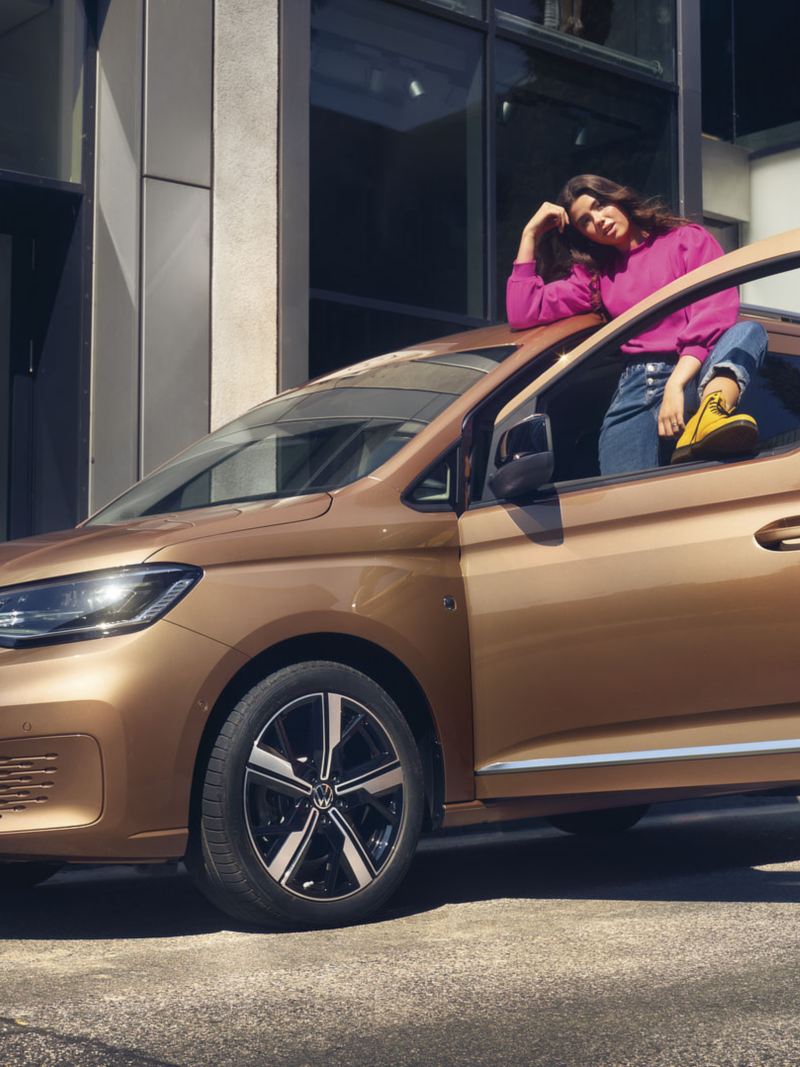 Una giovane donna appoggiata a Nuovo Caddy acquistato con le promozioni Volkswagen