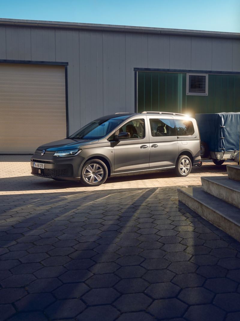 Una station wagon Volkswagen Caddy con rimorchio è parcheggiata davanti a un complesso residenziale.
