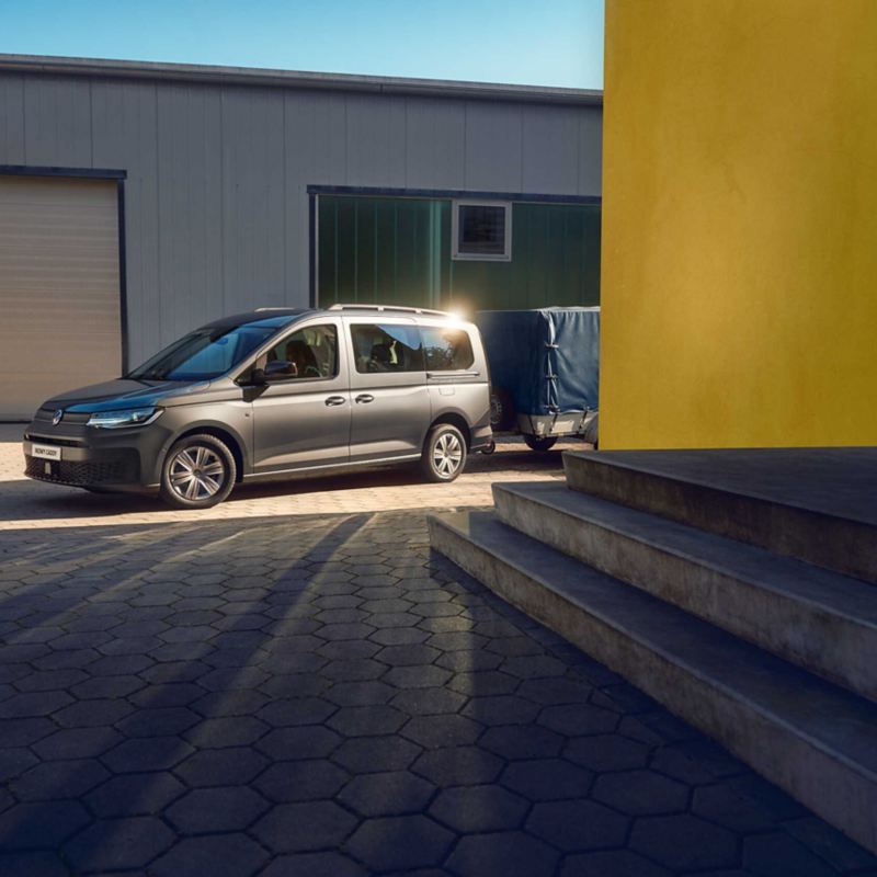 Volkswagen Samochody Dostawcze Caddy Kombi z przyczepą przed kompleksem mieszkaniowym.
