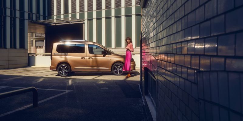 Kvinna lutar sig mot en VW Caddy familjebil