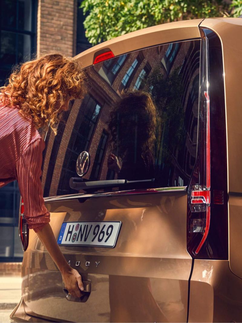 Женщина открывает багажное отделение нового VW Caddy