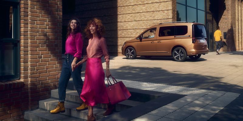 Two women running. The new Caddy in the background.