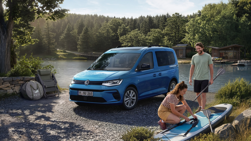 Ein grauer VW Caddy in der Heide mit Familie beim Picknick und Fußball spielen