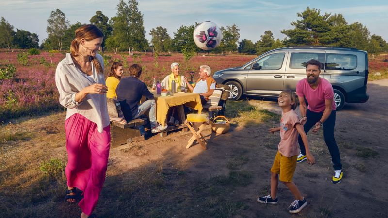 Ein VW Caddy in der Heide mit Familie beim Picknick.