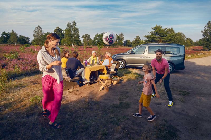 VW Caddy Kombi obok rodziny na pikniku.