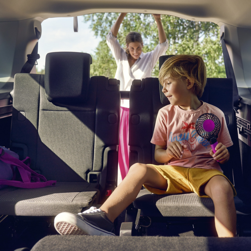 Två barn bak i en VW Caddy.
