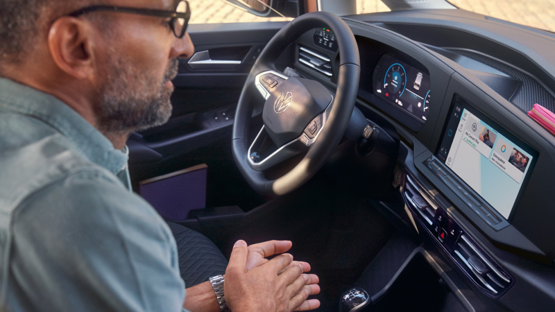 Mężczyzna siedzi na przednim siedzeniu pasażera i korzysta z usług VW Connect.