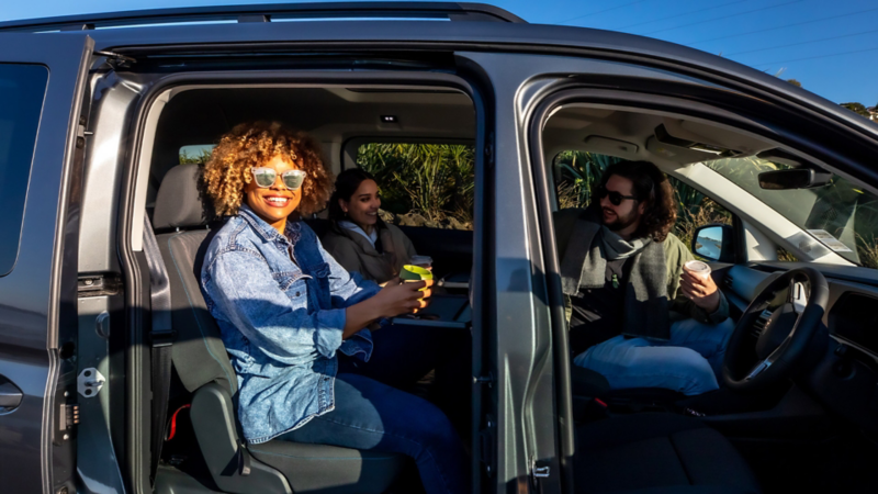  Drei Personen unterhalten sich in einem geparkten VW Caddy