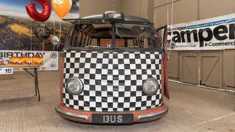 Photo showing the front of a VW Samba van next to a table with party treats on it. 