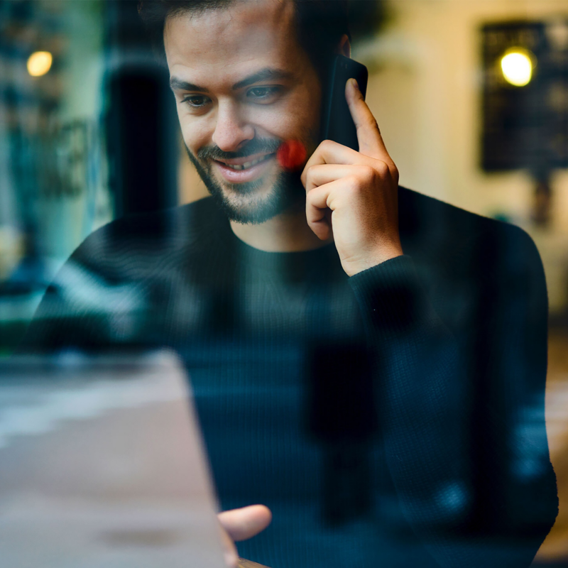 man at computer using phone in public area