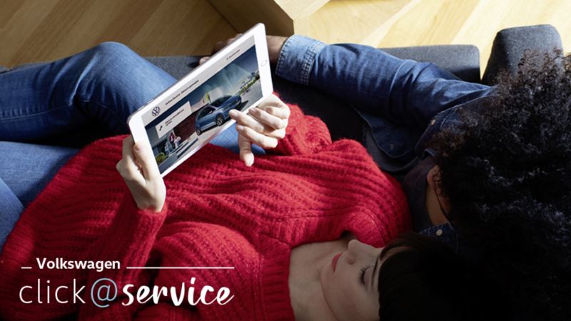 Ένα ζευγάρι έχει ξαπλώσει στον καναπέ και κοιτάζει τις υπηρεσίες Click&Service Volkswagen - Υπηρεσία MyServiceNow