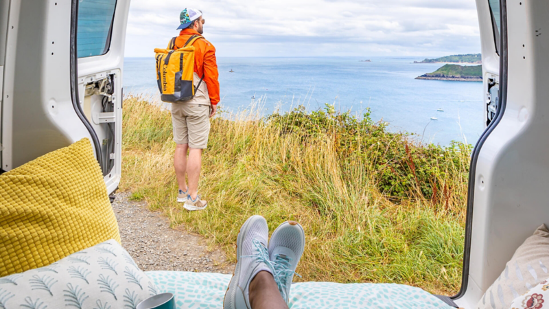 Photo vue depuis l'arrière du van avec un homme qui regarde la vue vers la mer.