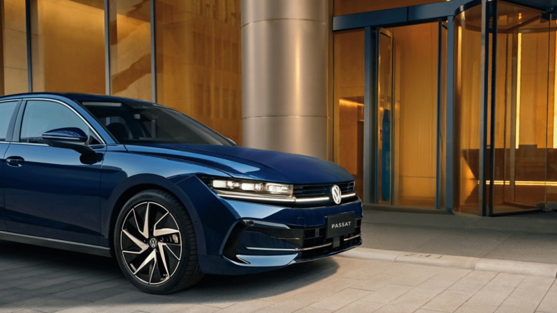 Blue passat next to glass building