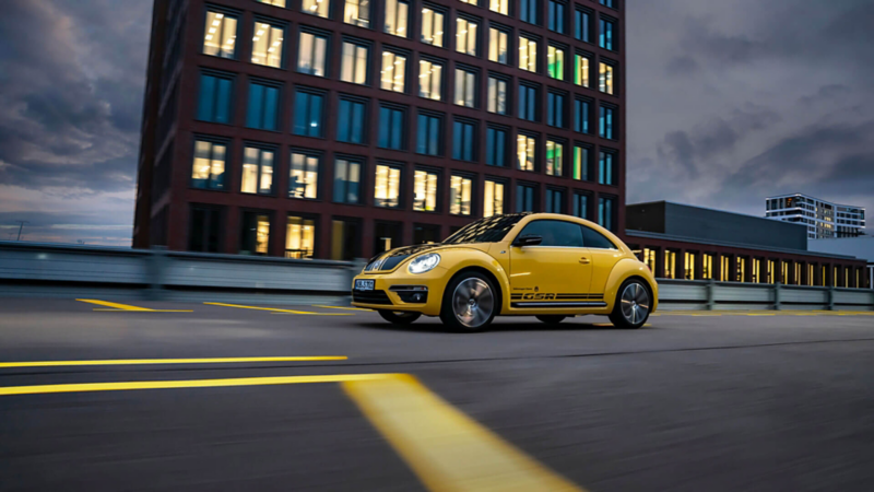 Vue de la Beetle GSR jaune et noire roulant de nuit sur une route urbaine.