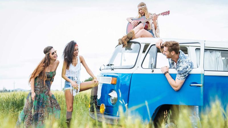 Amigos felices cantando junto a combi VW color azul