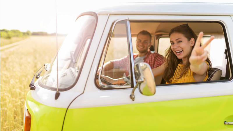 Pareja joven a bordo de una Combi Volkswagen verde