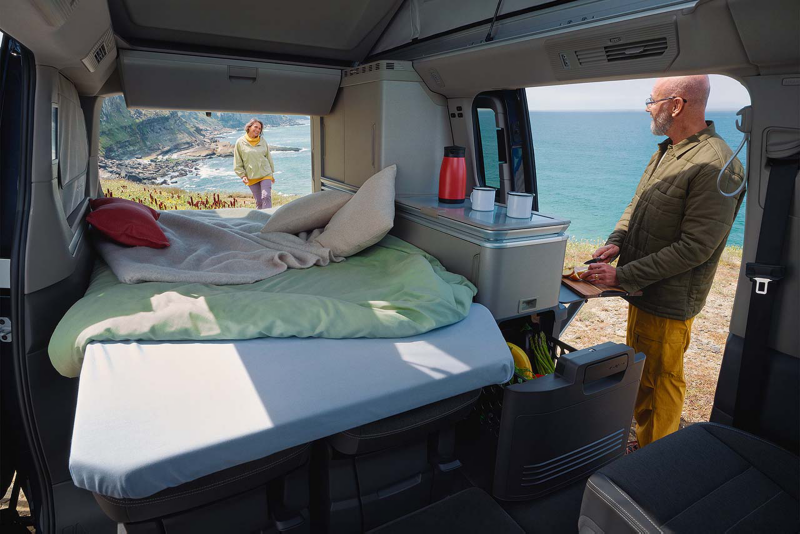 Detalle del interior de una furgo California con las puertas abiertas y la cama desplegada