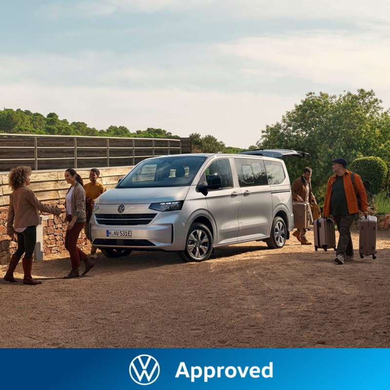 Una furgoneta Volkswagen Approved aparcada en un ambiente rural con gente a su alrededor descargando maletas