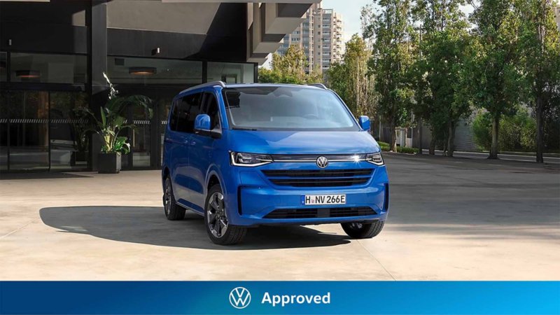 Un e-Caravelle de ocasión Volkswagen aparcado en un espacio citadino con el logo de Approved debajo