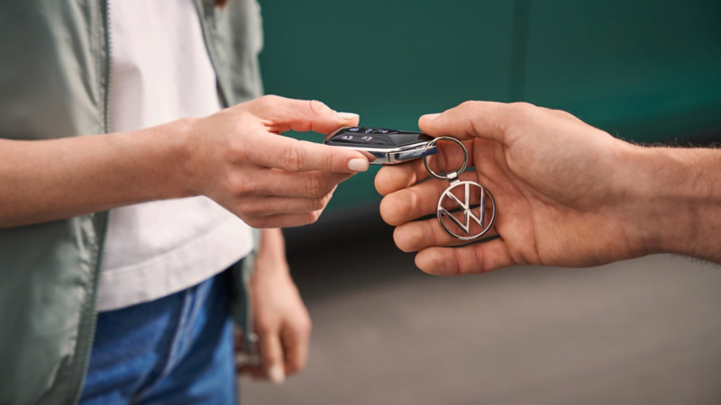 Manos de dos personas pasándose la llave de una furgo de Volkswagen