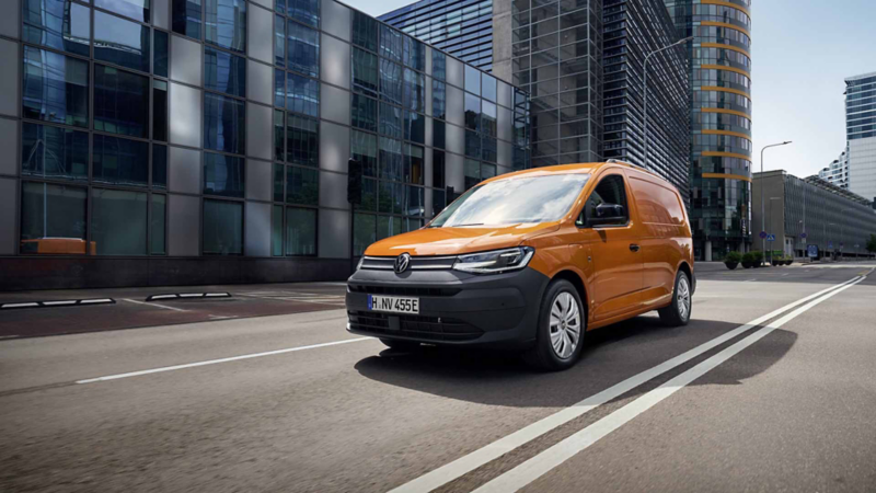 Primer plano de un VW Caddy Cargo junto a dos autónomos profesionales cargando material.