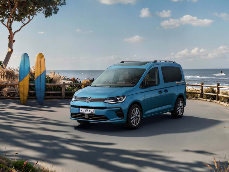 El Nuevo Caddy de Volkswagen aparcado en un ambiente playero y dos tablas de surf