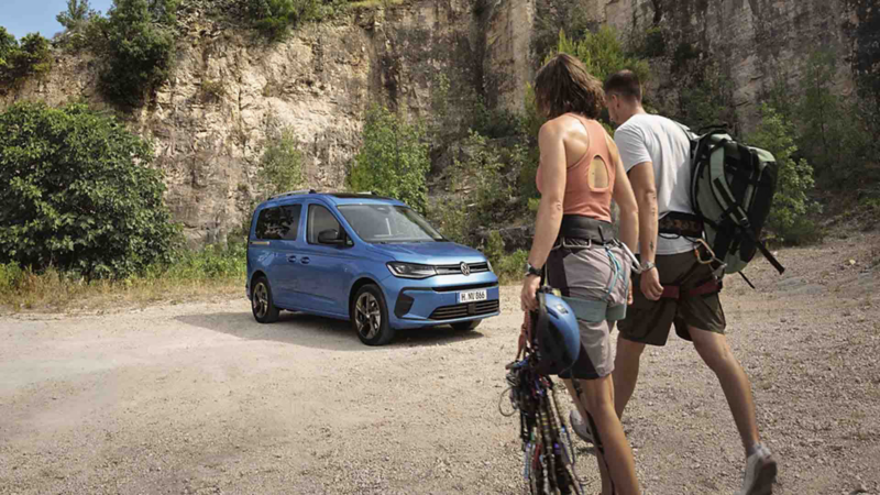 El Nuevo Caddy de Volkswagen aparcado en un ambiente natural y dos personas con ropa de trekking acercándose