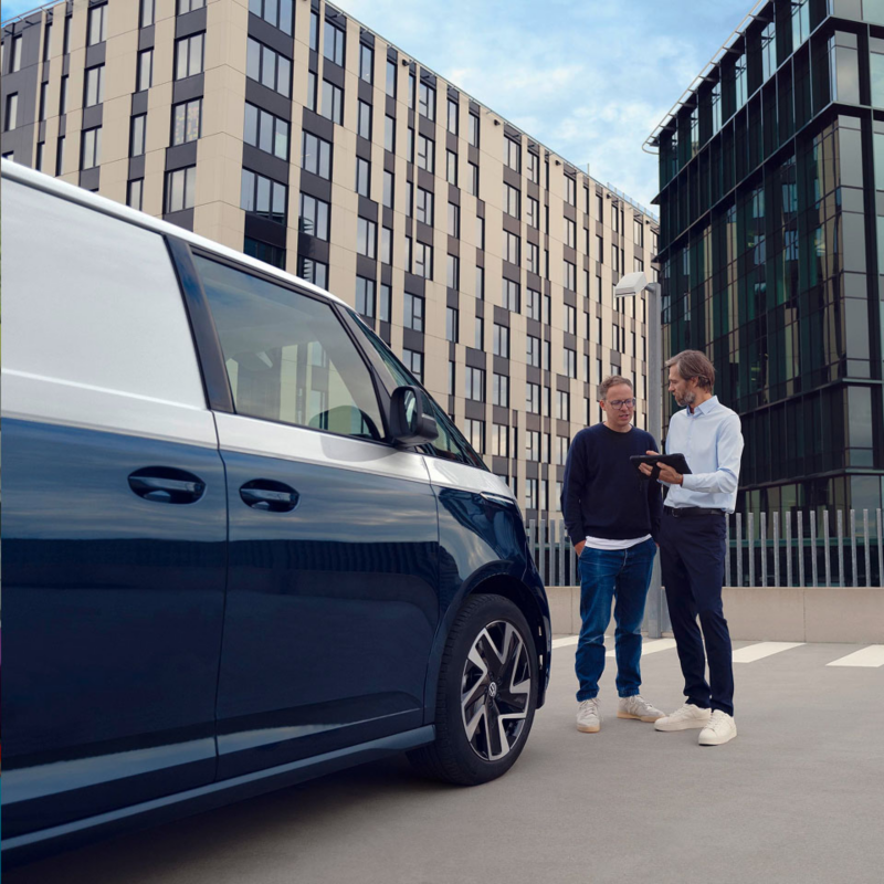 Dos hombre charlando frente una furgoneta Volkswagen azul