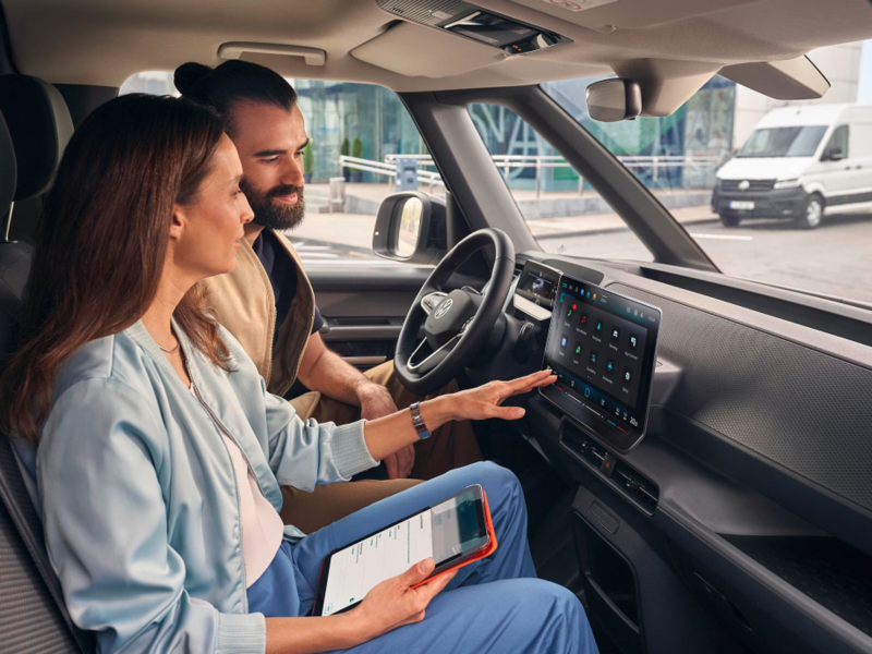 Una pareja manipulando la pantalla frontal del interior de un Volkswagen