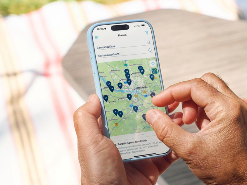 Una mano sujetando un móvil y buscando un concesionario Volkswagen en el mapa
