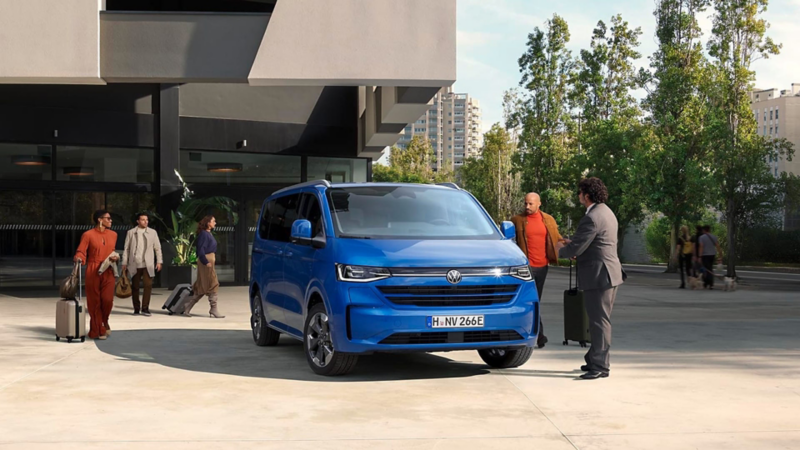 Personas con maletas junto a un Volkswagen e-Caravelle
