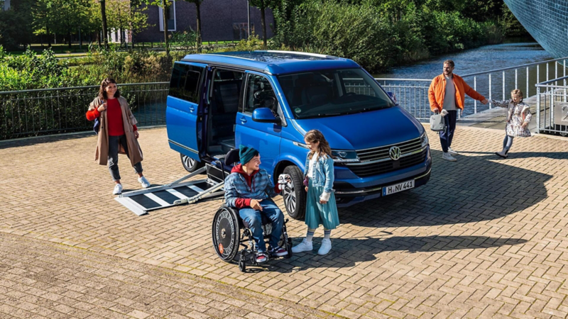 Personas junto a una Volkswagen Multivan con sistema de accesibilidad para sillas de ruedas
