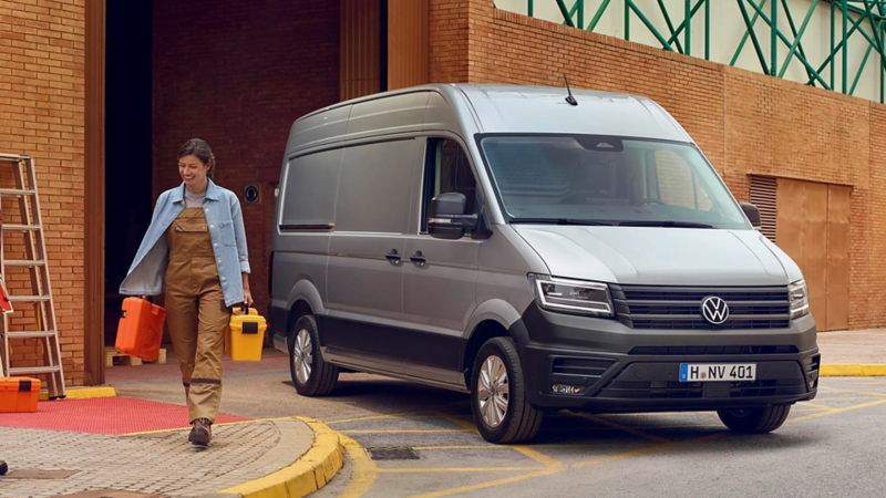 Una persona con herramientas junto a un Volkswagen Crafter gris