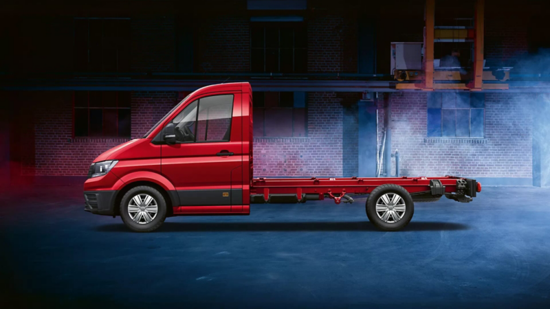 Una Volkswagen Crafter Chasis roja vista de costado frente a una fachada de ladrillo