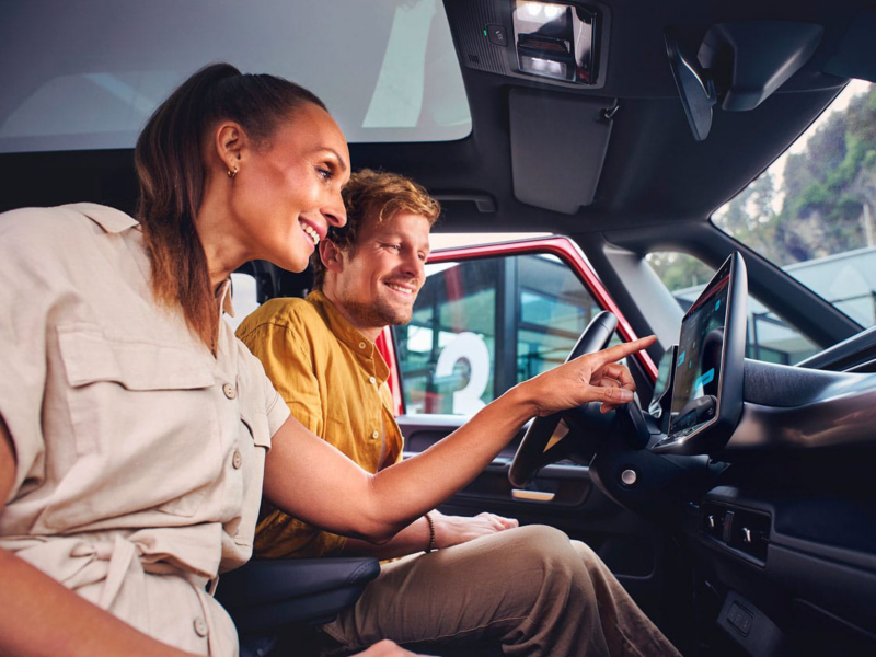 Dos personas en su furgo VW tocando el sistema informativo