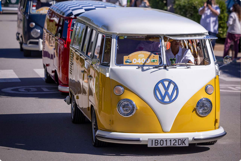 Una furgo clásica de Volkswagen amarilla y blanca caminando por la calle