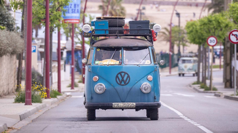 Una furgo clásica de Volkswagen color azul caminando por carretera