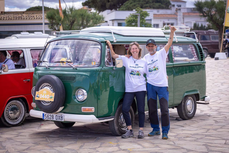 Una furgo clásica de Volkswagen color verde botella con dos personas cerca