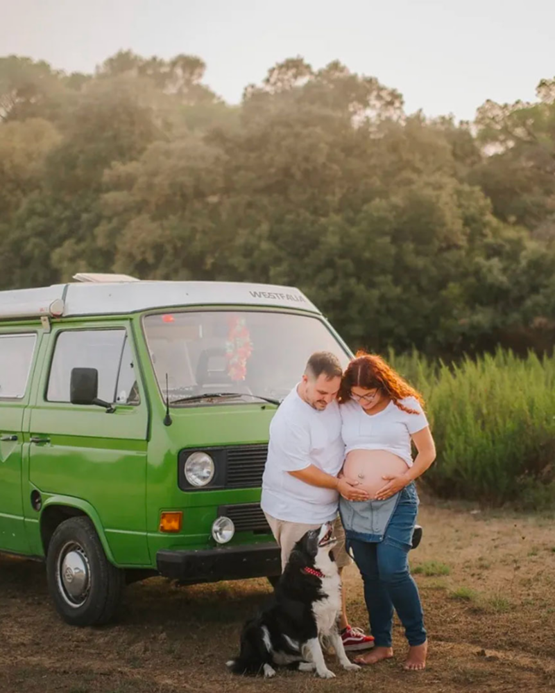 Historias The Originals dos personas delante de su furgo clásica Volkswagen aparcada en un paisaje natural mientras muestran el bebé en camino acompañados de su perro