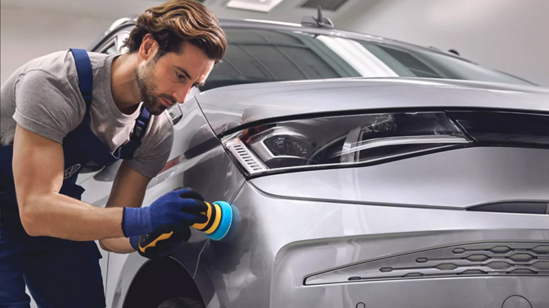 Un agente de servicio Volkswagen puliendo la pintura de una furgo