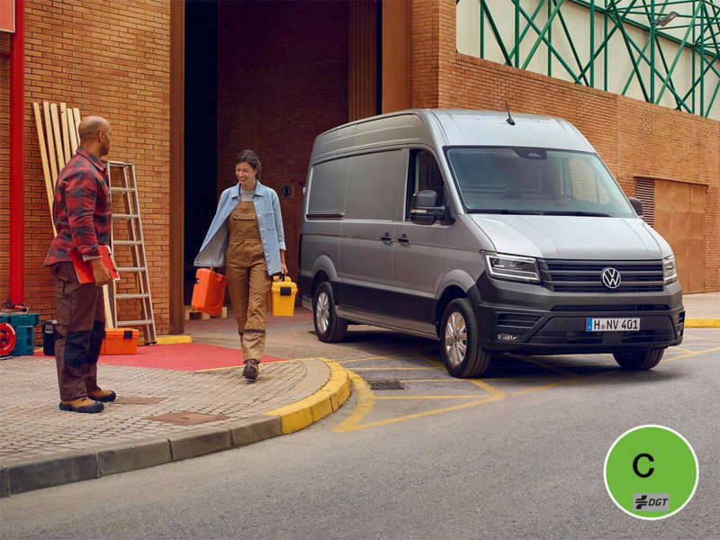 Nuevo Crafter aparcado en un ambiente laboral con dos trabajadores con materiales en las manos
