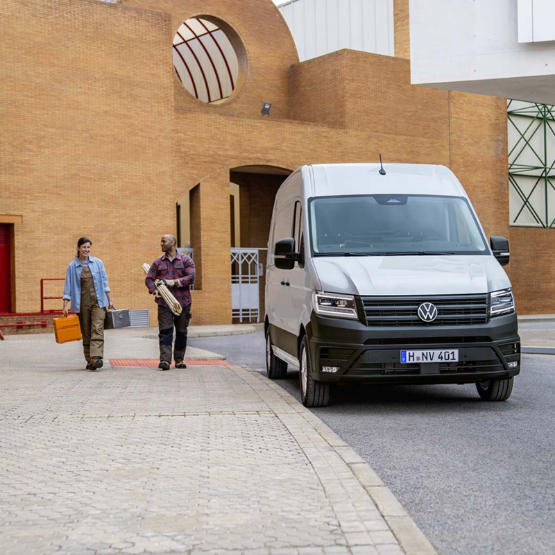 Una Volkswagen crafter aparcada en un entorno laboral con trabajadores cerca