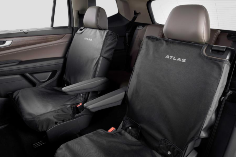 Front and rear seats of a Volkswagen Atlas equipped with black protective seat covers labeled “ATLAS”.